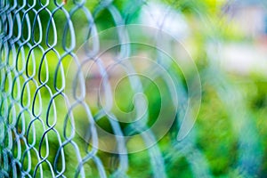 Metal mesh netting. Green blurred background. Bright colored bokeh