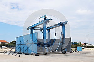 Metal mobile crane for launching small vessels and yachts. The iron structure is blue. Equipping of a seaport and a yacht marina.