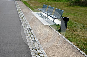 Metal modern park bench with a metal lightening structure on one leg stands in the park in rest areas and on roads made of