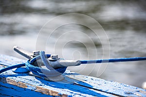 Metal mooring bracket on a wooden pier bar with wound mooring rope