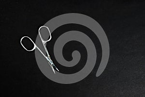metal nail scissors on a black textured background