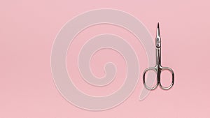 Metal nail scissors on a pink background