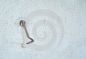Metal old hook on wall of house with empty space for insertion
