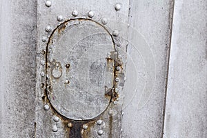 Metal old plate weathered gray rivets door oval part of the boat hull close-up industrial background design base