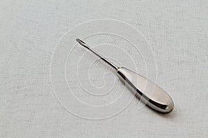 Metal old rare dental instrument for removing teeth on white gauze background. Black and white photo.