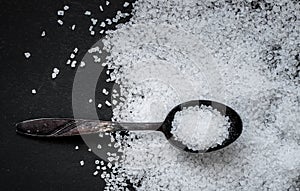 Metal old spoon with coarse sea salt on a dark background