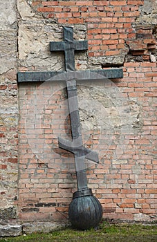 A metal Orthodox cross leaning against the wall of a church.