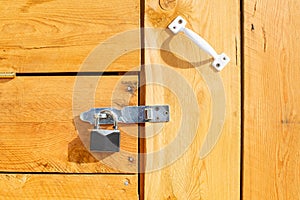 A metal padlock hangs on the wooden door of the house