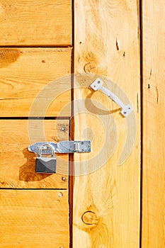 A metal padlock hangs on the wooden door of the house