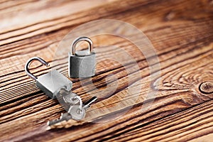 Metal padlock with silvered keys on old wooden background. Estate and security concept with symbol of protection.