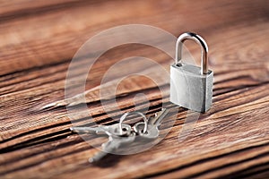 Metal padlock with silvered keys on old wooden background. Estate and security concept with symbol of protection.