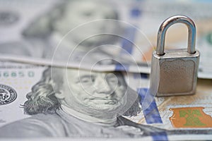 Metal padlock on 100 US dollars banknote background. Money stack for safety and investment. Saving and financial security concept