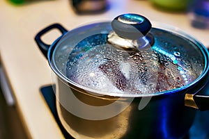 Metal pan with misted lid. Water droplets on the dishes during cooking on the electric stove. Close up. The view from