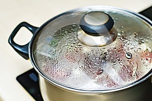 Metal pan with misted lid. Water droplets on the dishes during cooking on the electric stove. Close up. The view from