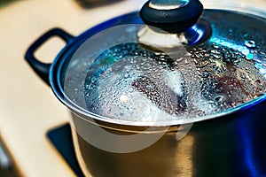 Metal pan with misted lid. Water droplets on the dishes during cooking on the electric stove. Close up. The view from