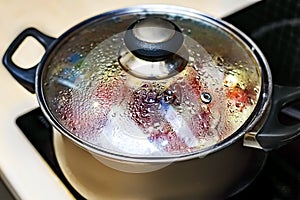 Metal pan with misted lid. Water droplets on the dishes during cooking on the electric stove. Close up. The view from the top