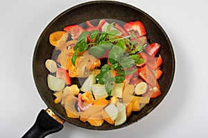 Metal pan with sliced red, yellow peppers, onions and basil branches