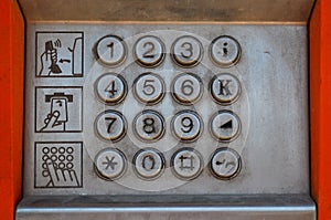 Metal panel of a street payphone with buttons and three pictograms with instructions for use