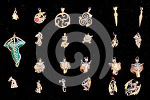 Metal pendants, close-up. Vintage amulets of gold with runes and in the form of animals on a black background