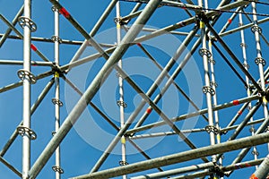 Metal pipe frame structure on blue sky background. Industrial construction from tubes raises upwards. Building process and joining