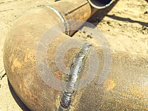 Metal pipe lies on the ground. underground communications. water withdrawal. rusty, old, dirty metal pipe with a solder joint from