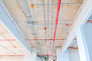 Metal pipes interior in Construction and fire sprinkler on red pipe are hanging from ceiling inside