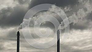 metal pipes of the plant against a gray sky, gray smoke comes out of the pipes