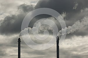 metal pipes of the plant against a gray sky, gray smoke comes out of the pipes