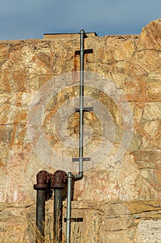 Metal pipes on water resevoir and conservation building made out of rock and stone in late afternoon sun with tubes