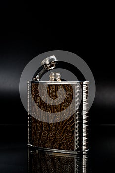 Metal pocket flask for alcoholic beverages, shot against a dark background