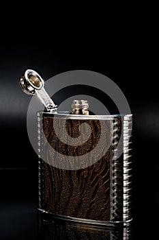 Metal pocket flask for alcoholic beverages, shot against a dark background