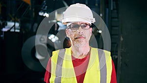 Metal-producing factory unit with a male employee looking at the camera