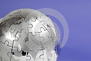 Metal puzzle globe on blue background