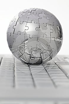 Metal puzzle globe on computer keyboard