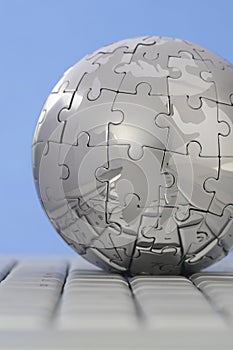 Metal puzzle globe on computer keyboard