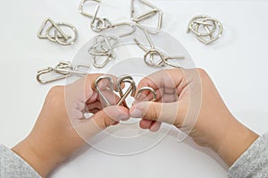 Metal puzzle in hands. White background. Close-up. Concept to solve the puzzle.