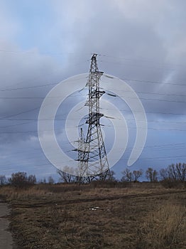 Metal pylons of a power line against a disturbing cloudy sky on the outskirts of a city. High voltage towers. Desolate