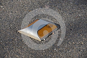 Metal road stud with yellow reflector on asphalt road in Thailand