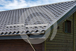 Metal roof construction on a wooden house. Rain gutter.