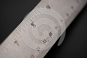 Metal ruler on a black leather  background with black numbers and scale. Show scale in black digit