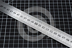 A metal ruler on the mark of 80 centimeters against the background of the grid on the cutting mat