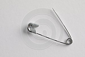 Metal safety pin on white background, top view