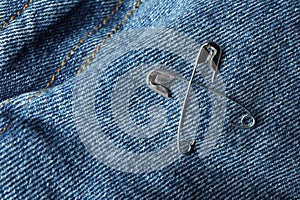 Metal safety pins on denim fabric, closeup