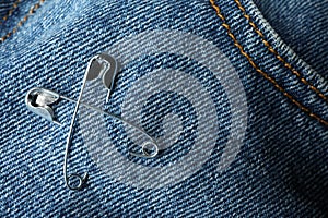 Metal safety pins on denim fabric, closeup