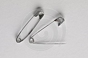 Metal safety pins on white background, flat lay