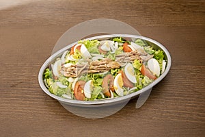 Metal salad tray to share with lots of iceberg lettuce, tomato and chopped boiled egg, slices of white onion and canned tuna on