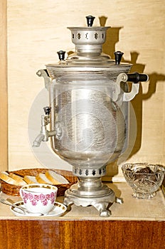 Metal samovar on an old wooden table and tea cup with spoon