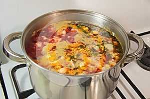 Metal saucepan with boiling vegetable soup on a gas stove