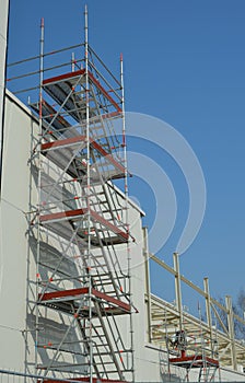 Metal scaffolding structures against a white building wall - vertical photograph