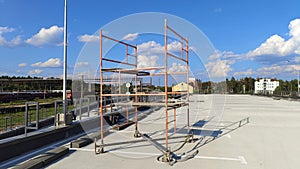 Metal scaffolding on wheels stands on the roof of the parking lot under construction. Nearby, at the station, electrified railroad